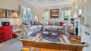 A living room with a sofa, a coffee table, a red cabinet, and a bookshelf. - 2 bedroom accommodation in Burpham, near Arundel (Burpham, near Arundel)