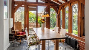 A spacious dining area with a wooden table, chairs, and a view of the garden through large windows. - 2 bedroom accommodation in Burpham, near Arundel (Burpham, near Arundel)