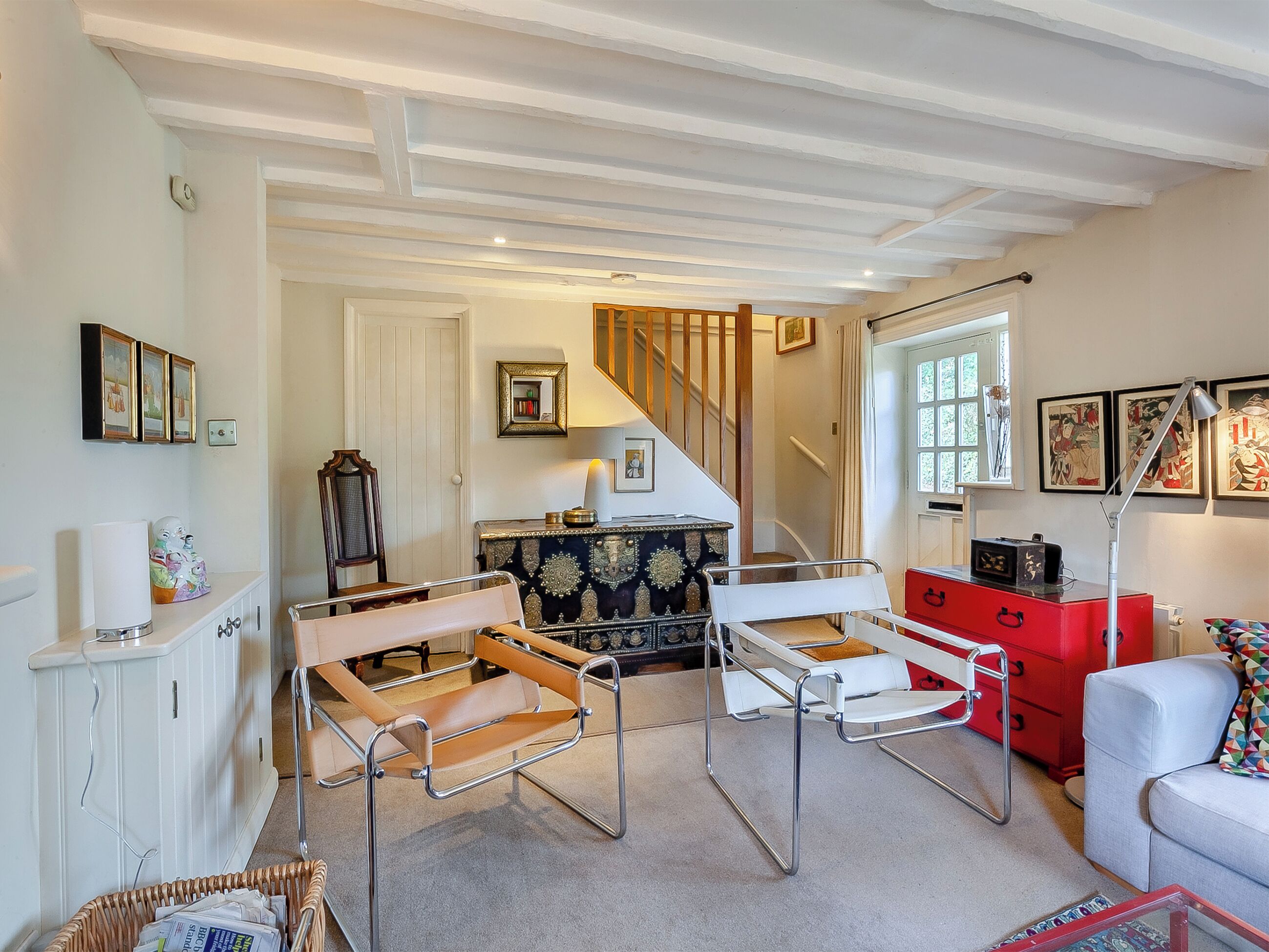 Ein Zimmer mit hohen Decken, einer Treppe, einem roten Schminktisch und einem weißen Sofa.