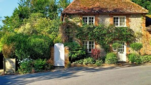 A stone house with a brick roof, surrounded by lush greenery and a clear sky. - 2 bedroom accommodation in Burpham, near Arundel (Burpham, near Arundel)