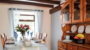 A dining area with a table set for four, a vase with flowers, and a fruit bowl on a wooden cabinet. - 2 bedroom accommodation in Buckton, near Bridlington (Buckton, near Bridlington)