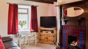 A living room with a fireplace, a television, and a sofa. - 2 bedroom accommodation in Buckton, near Bridlington (Buckton, near Bridlington)