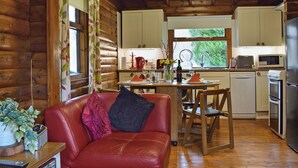 Ein rustikales Holzhaus-Interieur mit Essbereich, Küche und einem roten Ledersofa.