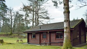 Eine Blockhütte mit Kiesterrasse, einem Picknicktisch und einer Holzbank.