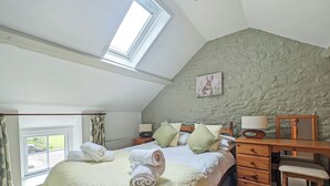 A bedroom with a skylight, a bed with pillows, a desk with a lamp, and a chair. - 2 bedroom accommodation in Llannon, Llanelli (Llannon, Llanelli)
