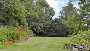 A grassy area with a stone wall and dense foliage. - 2 bedroom accommodation in Llannon, Llanelli (Llannon, Llanelli)
