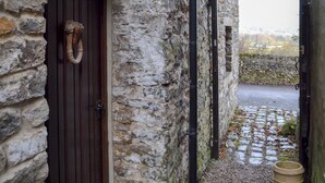 A stone building with a wooden door and a metal gate. - 1 bedroom accommodation in Castleton (Castleton)
