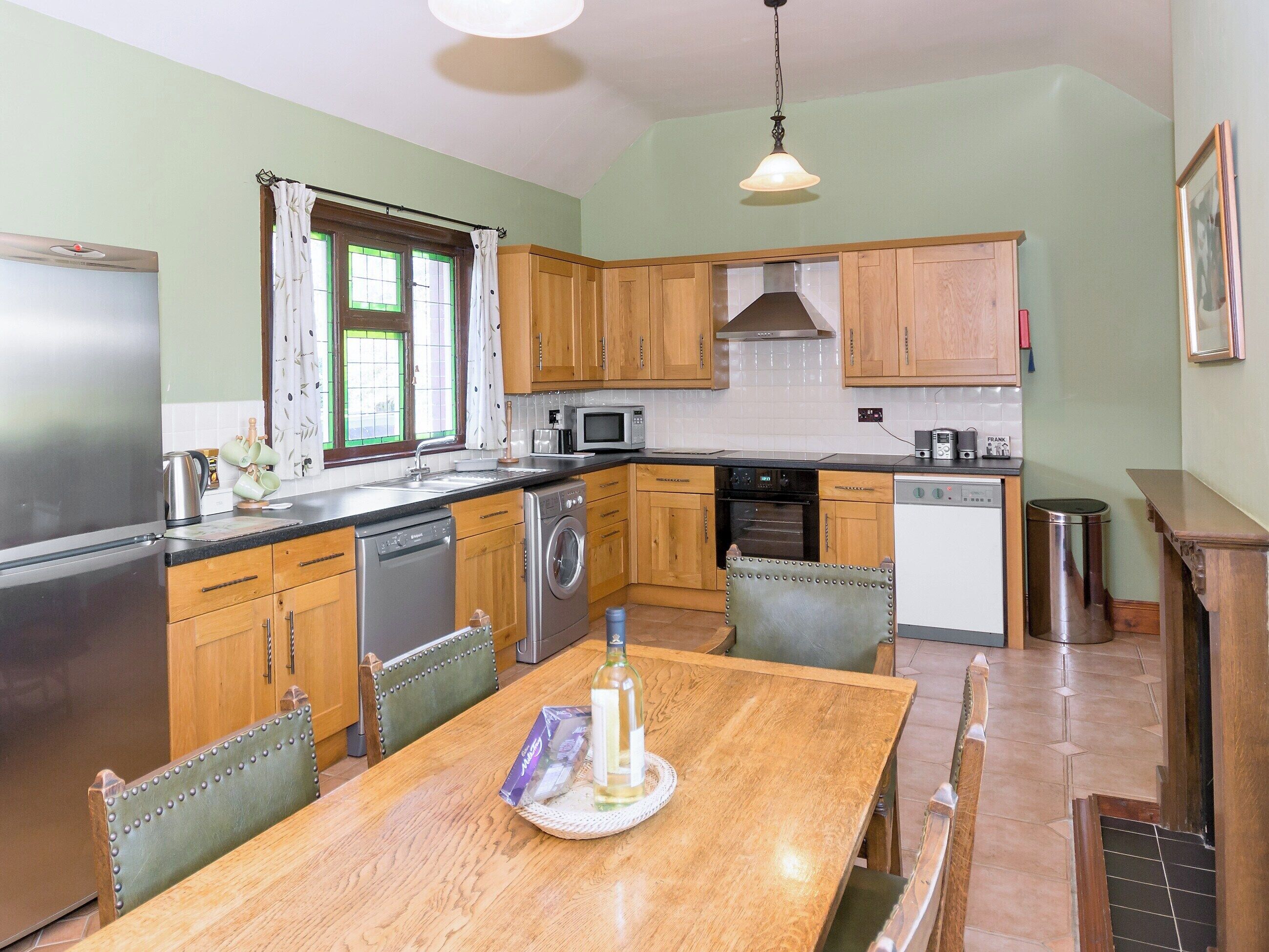 A kitchen with wooden cabinets, a stainless steel refrigerator, a dishwasher, and a dining table with chairs.