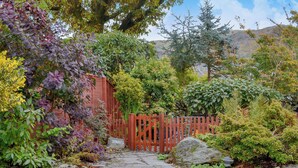 A stone pathway leading to a wooden gate labeled 'STABLES' surrounded by lush greenery and a mountainous backdrop. - Coach House Grasmere (Grasmere)