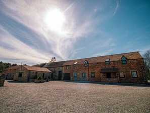 A historic building with a gravel courtyard, featuring a traditional brick facade and multiple windows.