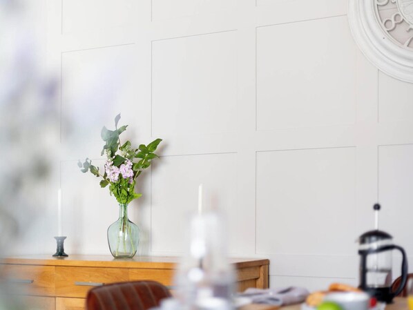 Une commode en bois, sur laquelle sont posés un vase de fleurs et une bougie.