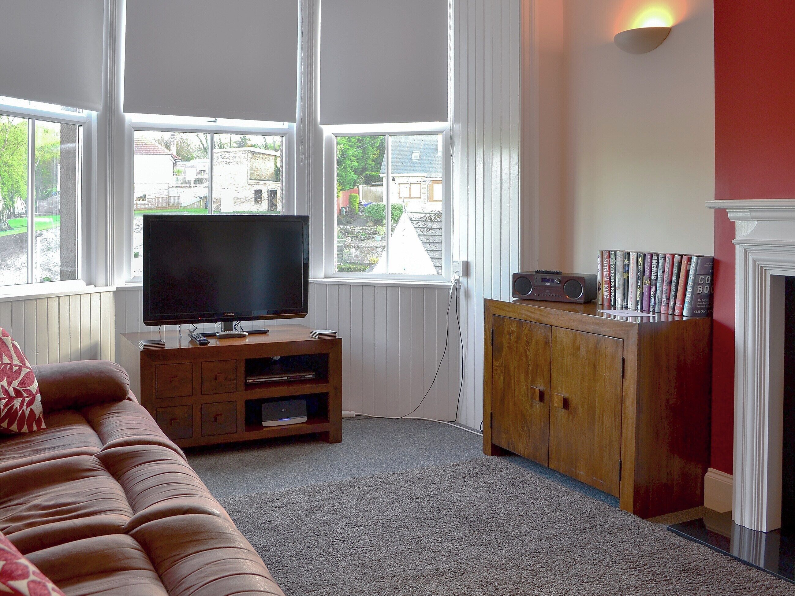 A living room with a television, wooden cabinet, and books.