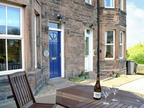 A stone building with a blue door, a wooden chair, and a table with a bottle and glasses. - 3 bedroom accommodation in Wooler (Wooler)