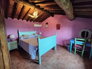 Una habitación con cama, una silla, una mesita de noche y aire acondicionado instalado en la pared.