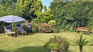 A garden with a lawn, two striped lounge chairs, a wooden bench, and a potted plant. - 3 bedroom accommodation in Fitzhead, near Wivelscombe (Fitzhead, near Wivelscombe)
