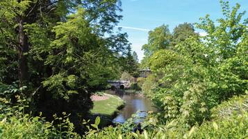 A river flowing through a lush, green landscape with a bridge and gazebo.