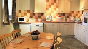 Une cuisine de taille réduite, avec une table en bois, des chaises, un four à micro-ondes, un grille-pain et un évier.