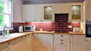 A kitchen with white cabinets, a microwave, a toaster, and a red-tiled backsplash. - 1 bedroom accommodation in Moffat (Moffat)