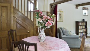 A dining area with a round table covered in a pink tablecloth, surrounded by wooden chairs. A floral vase with pink flowers is placed on the table. - 2 bedroom accommodation in Aston Cantlow, near Stratford (Aston Cantlow, near Stratford)
