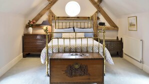 A bedroom with a wooden bed, a nightstand, a dresser, a radiator, and a ceiling light fixture. - 2 bedroom accommodation in Aston Cantlow, near Stratford (Aston Cantlow, near Stratford)