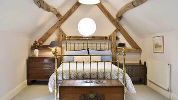 Une chambre à coucher avec un lit en bois, une table de chevet, une commode, un radiateur et un luminaire au plafond.