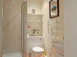 Ein Badezimmer mit Dusche, Toilette, Waschbecken und Ablagen für Toilettenartikel.