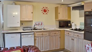 A kitchen with white cabinets, a microwave, a stove, and a dishwasher. - 1 bedroom accommodation in Cromford, near Matlock (Cromford, near Matlock)