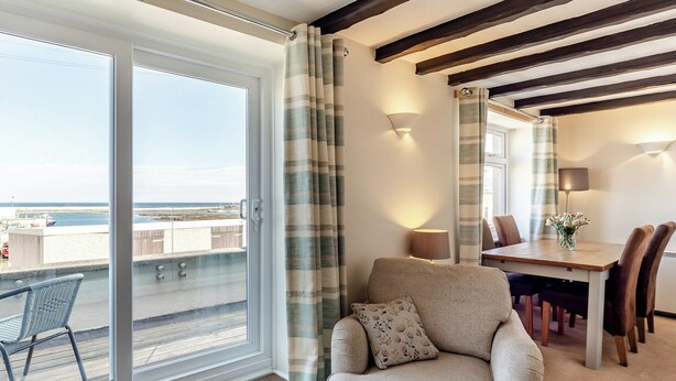 Een kamer met balkon, eethoek en een bank.
