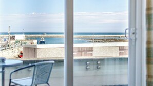 Een balkon met uitzicht op zee, een boot en een gebouw met een hijskraan.