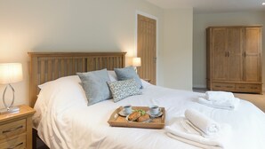 A neatly made bed with pillows, a tray with croissants and coffee, and a wooden wardrobe in a hotel room. - 3 bedroom accommodation in Ventnor (Ventnor)
