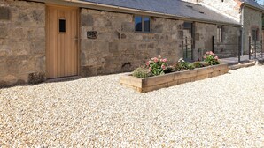 A stone building with a wooden door, a number '2' sign, and a gravel driveway. - 3 bedroom accommodation in Ventnor (Ventnor)