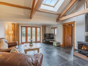 A living room with a fireplace, a sofa, a TV, and a skylight. - The Cart House - HNNH (Hartland)