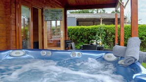 Un jacuzzi en una cabaña de madera con una puerta de cristal que da a un patio.