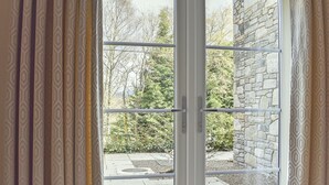 Une porte-fenêtre coulissante donnant sur un patio extérieur agrémenté d’un mur en pierre et de verdure.