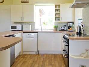 Eine kompakte Küche mit weißen Schränken, einer Mikrowelle, einem Geschirrspüler, einem Toaster und einem Wasserkocher.