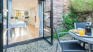 Una cucina moderna con mobili bianchi, un tavolo da pranzo con sedie e vista sull'interno attraverso una porta aperta.