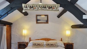 Um quarto aconchegante com uma cama de madeira, duas luminárias de cabeceira, um quadro na parede e um tapeçaria sobre a cama.