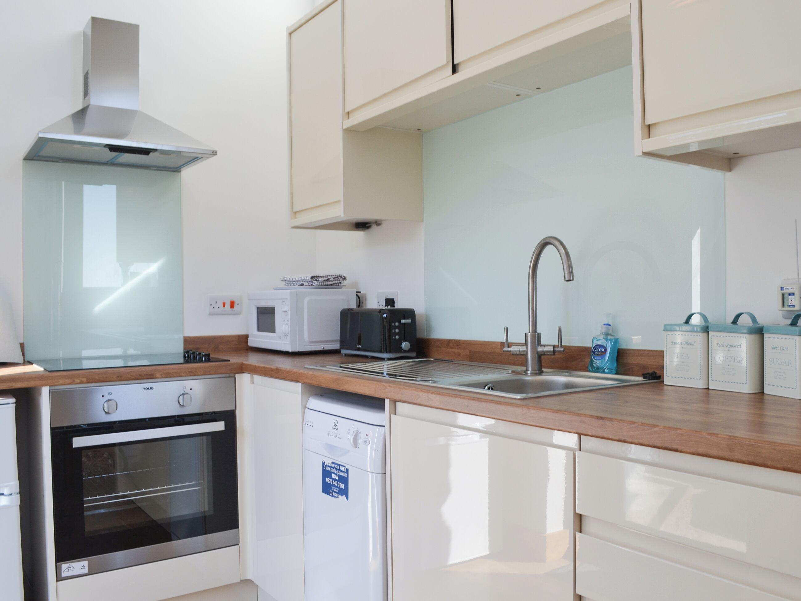 A modern kitchen with a dishwasher, oven, microwave, toaster, and a stainless steel sink.