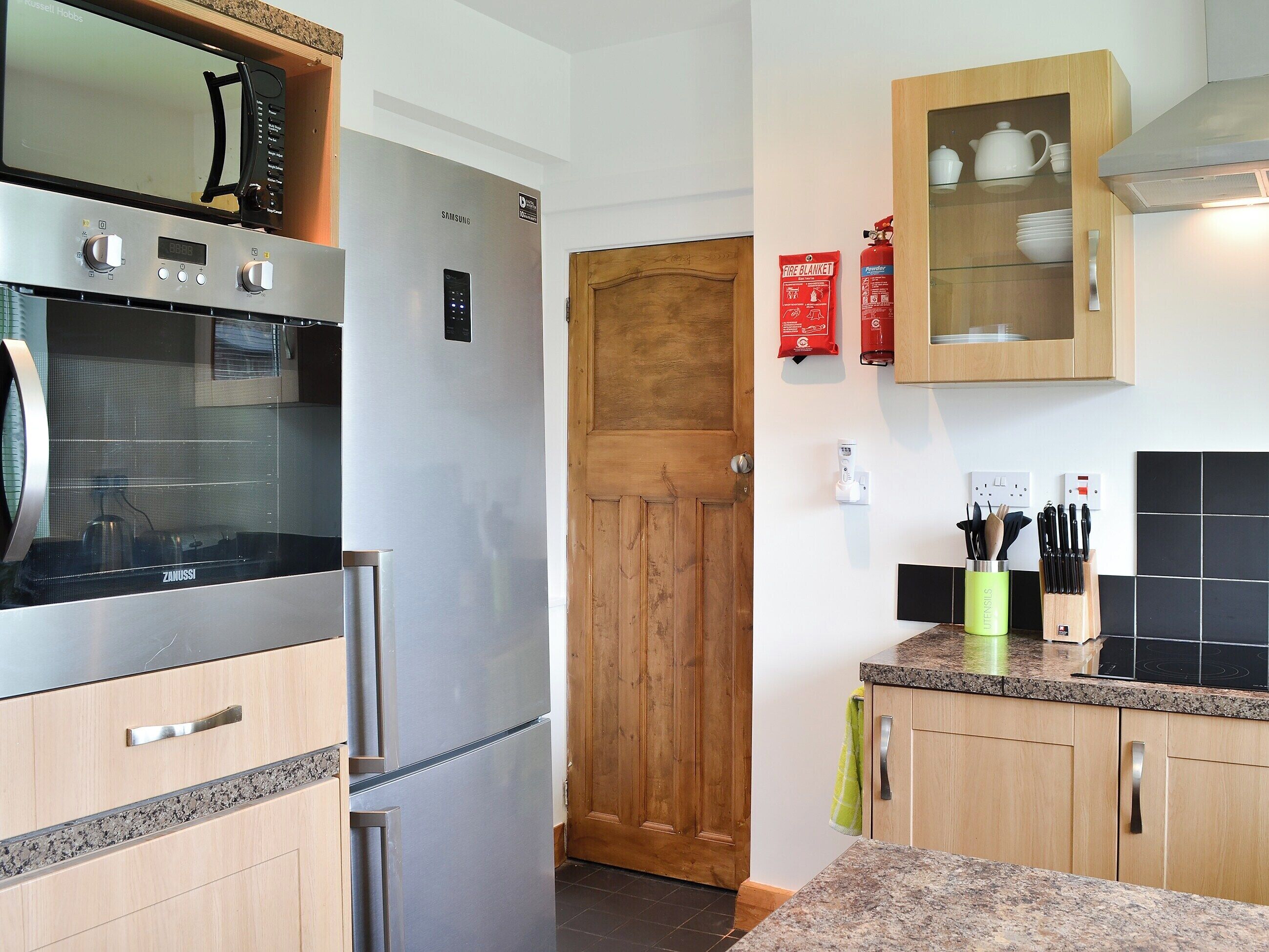 Eine moderne Küche mit Edelstahlgeräten, Holzschränken und einer Arbeitsplatte aus Granit.