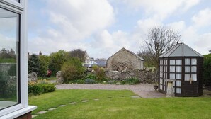 Un jardin agrémenté d’un bâtiment en pierre, d’une structure en bois et d’un mur en briques.