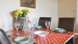 Een eettafel gedekt met borden, glazen en een bloevas.