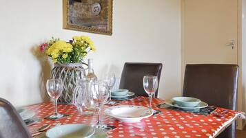 A dining table set with plates, glasses, and a vase of flowers.