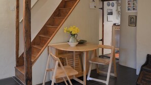 Un escalier en bois, avec une petite table et des chaises, dans une pièce dont le sol est recouvert de carreaux.