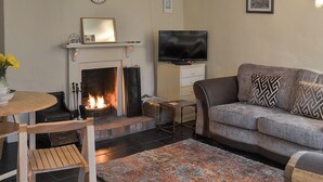 Un salon avec une cheminée, un téléviseur, un canapé et une table basse.