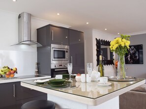 A modern kitchen with a built-in microwave, oven, and stainless steel range hood.