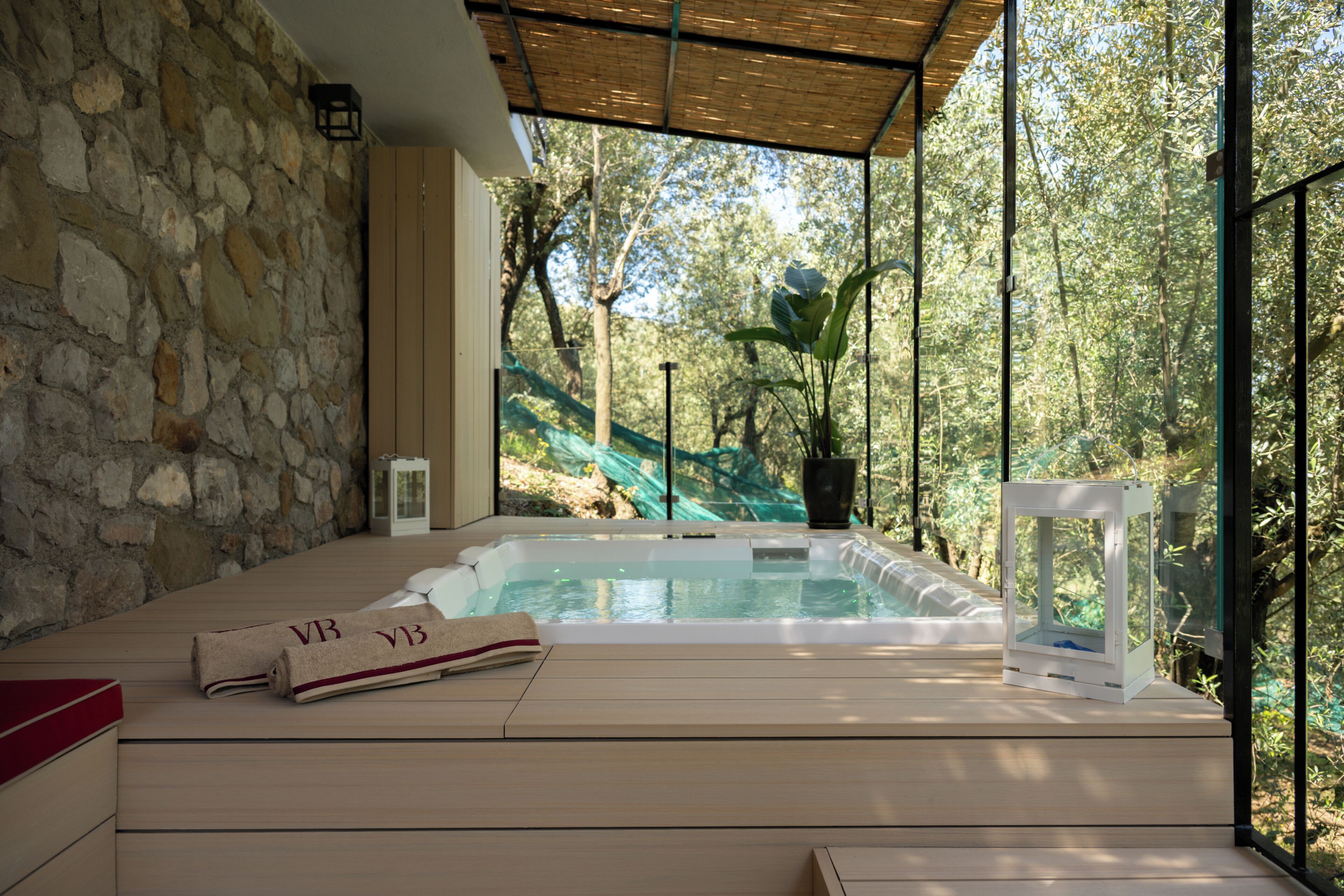 A spa area with a hot tub, stone walls, and a view of trees.
