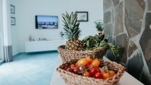 Una cocina con pared de piedra, encimera blanca y televisión en la pared.