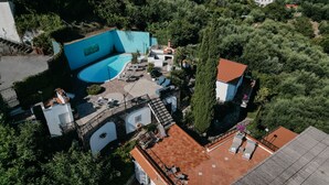 Vista aérea de una propiedad con piscina, mobiliario de exterior y jardín.