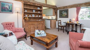 Ein gemütliches Zimmer mit einem Holzkasten, einem Esstisch und einem rosa Sessel.