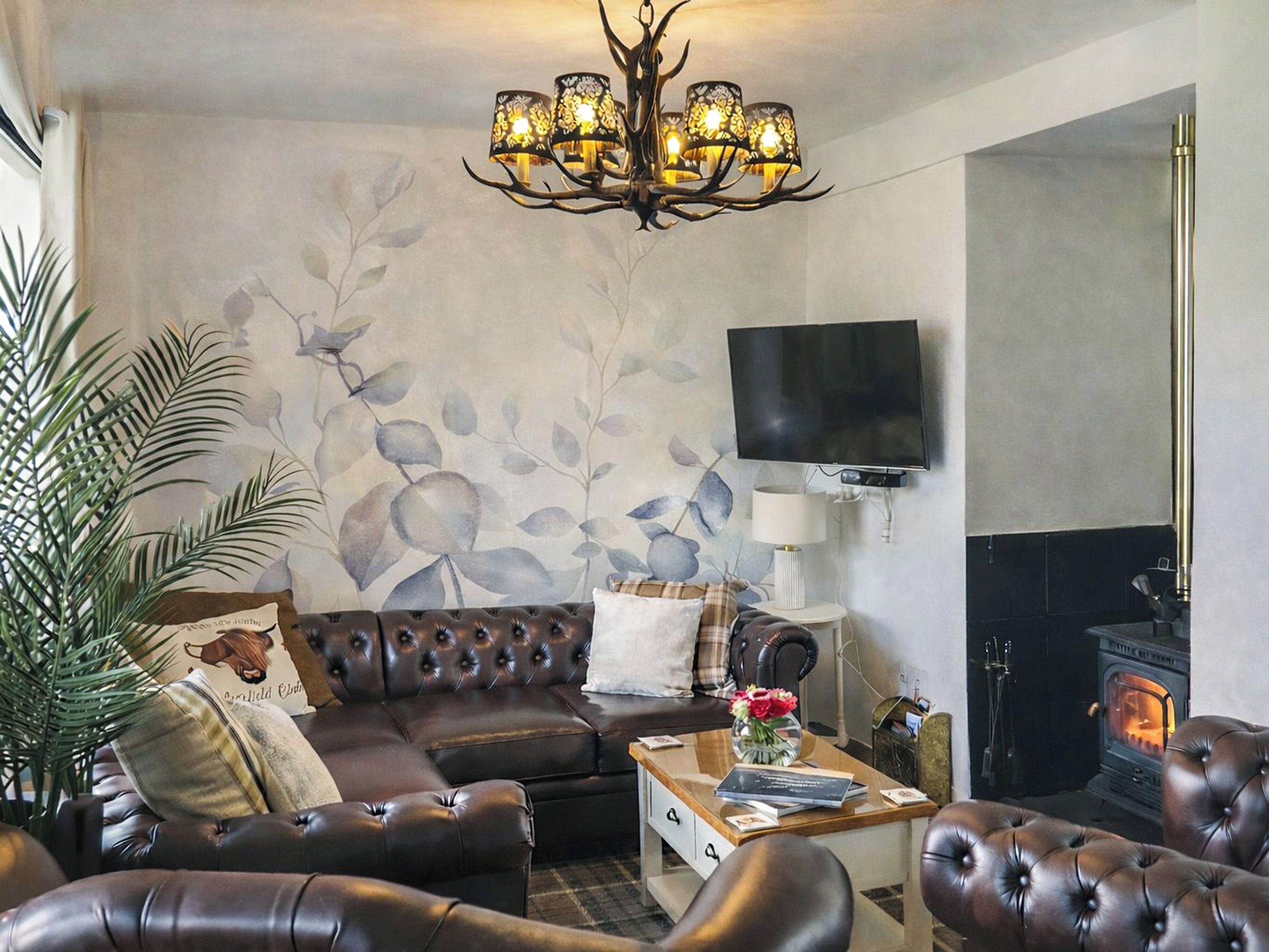 Ein Wohnzimmer mit Kamin, einem an der Wand befestigten Fernseher und einer Kristallleuchtre.